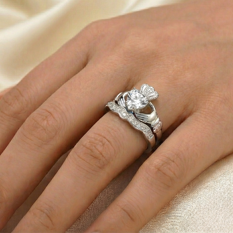 Silver ring with a large heart on a hand against a beige fabric background