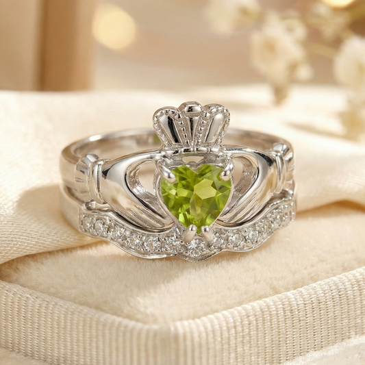 Silver claddagh ring with a green gemstone on a beige fabric background