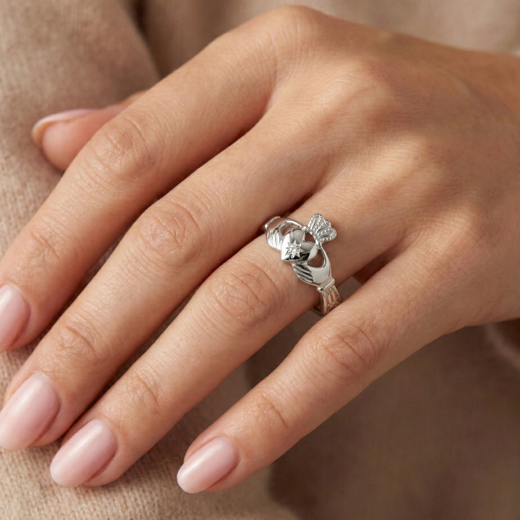 Silver claddagh ring on a person's finger against a beige background