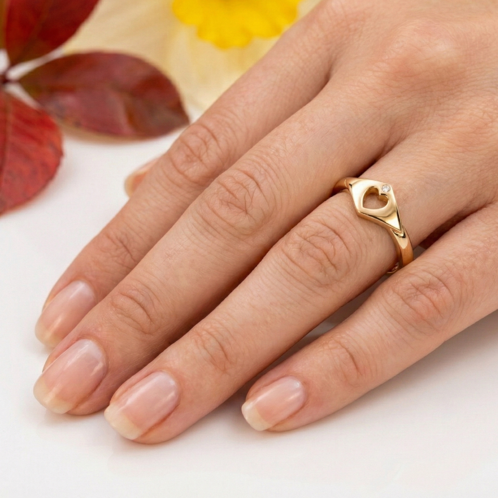 Hand wearing a gold modern claddagh ring with a geometric design on a light background