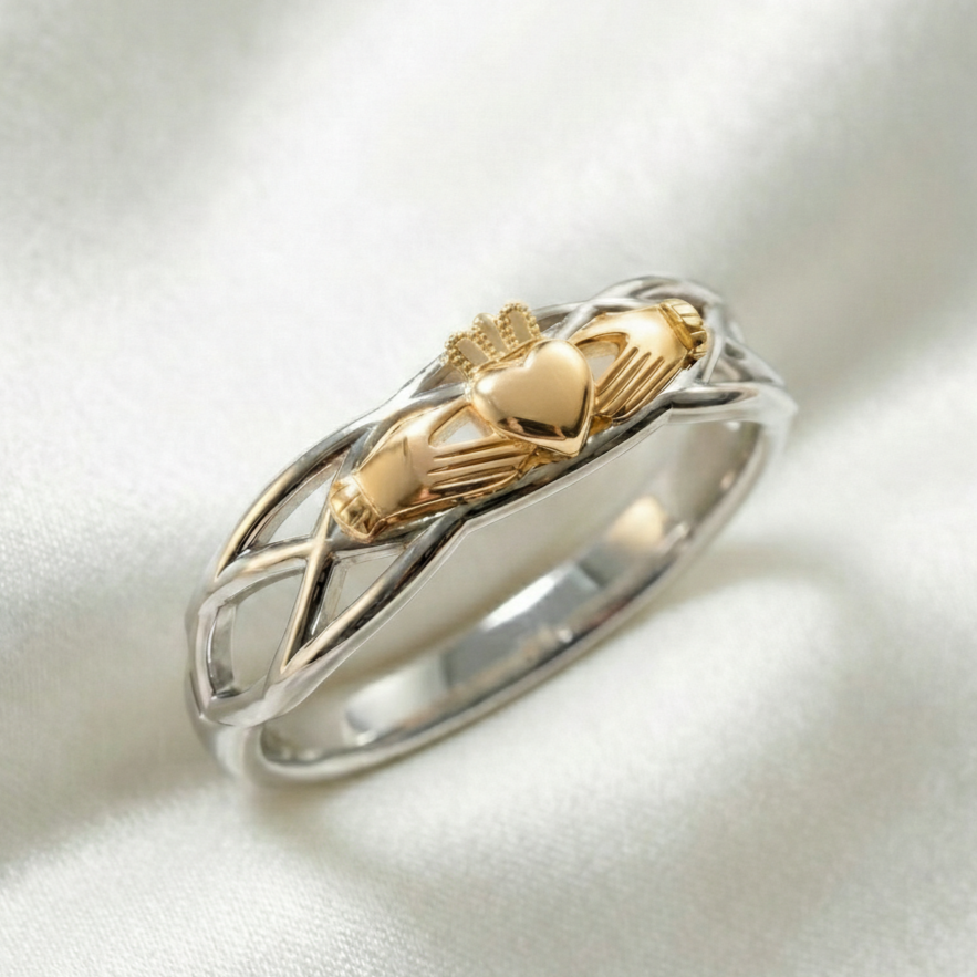 Gold and silver ring with claddagh design on a white background