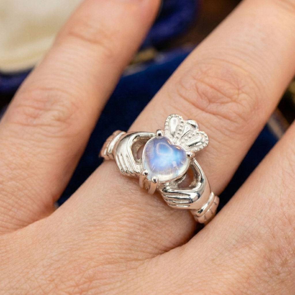Silver claddagh ring with a heart-shaped moonstone gemstone on a finger